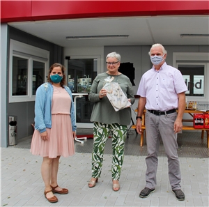 Regina Hertlein, Vorstandsvorsitzende des Caritasverbands Mannheim (Mitte), überreicht einen Anker als Geschenk an Manuela Morsch (Caritas) und Bernd Bung (Drogenverein), Koordinationsleitung des Café