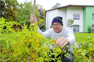 Ein Mitglied der Gartengruppe mit selbst gepflanzten Tomaten