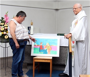 Eine Bewohnerin zeigt im Gottesdienst ein von ihr selbst gemaltes Bild.