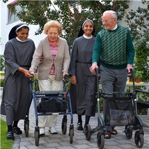 Zwei Ordensschwestern, eine Bewohnerin und ein Bewohner laufen zusammen durch den Garten