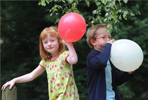 Ein Mädchen und ein Junge mit Luftballons