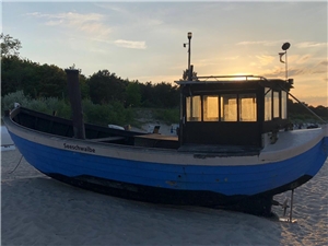 Fischerboot am Strand im Sonnenuntergang