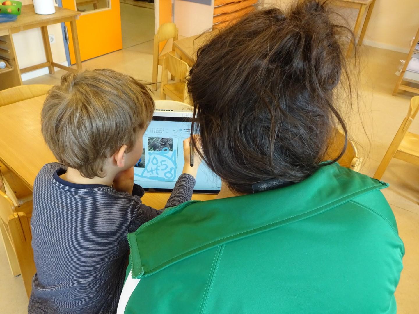 Erzieherin arbeitet mit Kind am Notebook