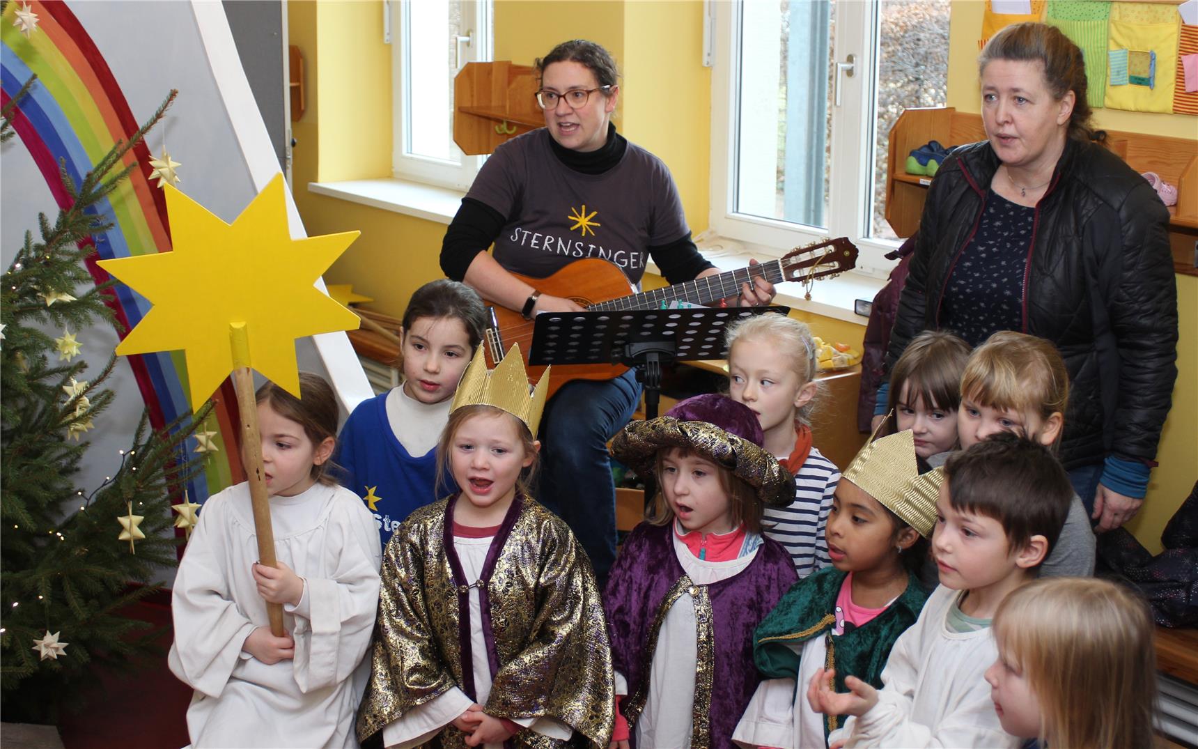 Kinder sind als Sternsinger verkleidet und singen Lieder