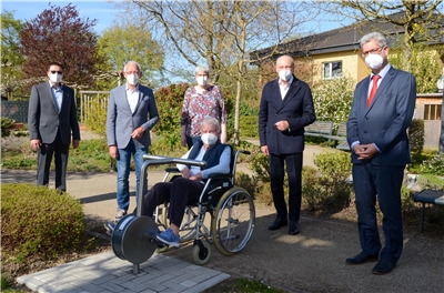 Bewohnerin Irmgard Siedschlag zeigt den Vertretern der Caritas-Stiftung Mönchengladbach, wie gut sie den neuen Radtrainer des Caritaszentrums Holt nutzen kann.