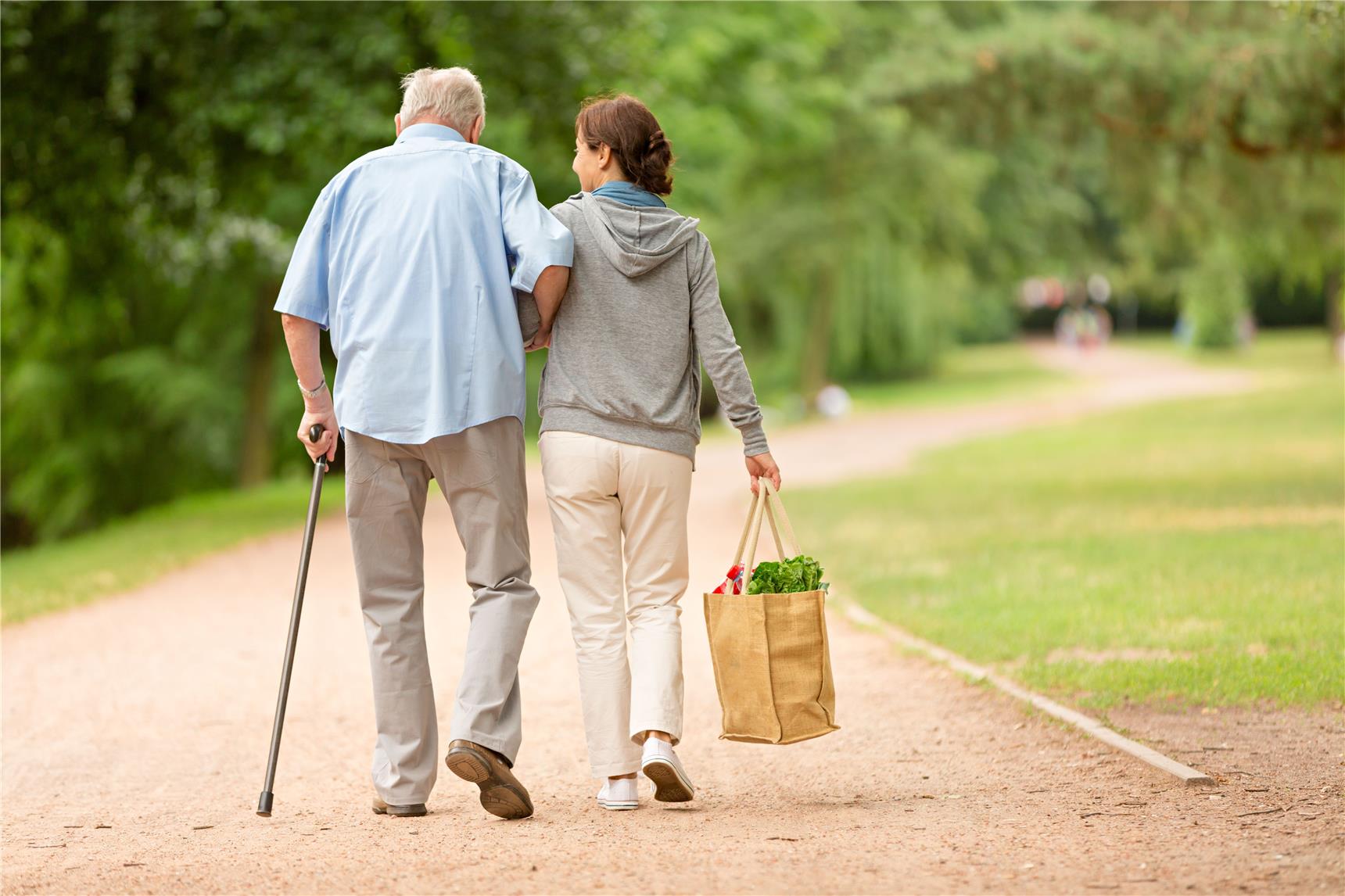 Seniorenbegleiterin und älterer Mann gehen spazieren