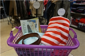 Ein mit verschiedenen Kleidungsstücken gefüllter Korb steht auf dem Tresen der Kleiderkammer