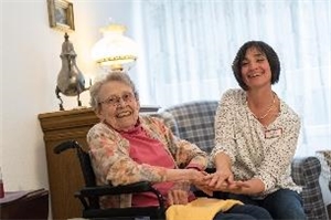 Eine Betreuerin und eine Seniorin lächeln in die Kamera