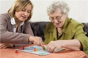 Eine Ehrenamtliche spielt mit einer Seniorin ein Brettspiel