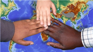 Drei Hände unterschiedlicher Hautfarbe liegen auf einer Weltkarte