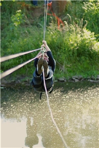 Ein Mann benutzt gerade mit Karabinern festgezurrt die Seilbahn
