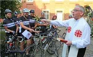 Weihbischof Geerlings steht vor einer Gruppe Radfahrer