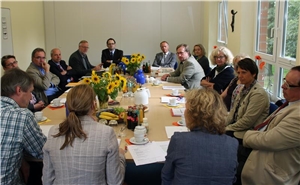 Das Foto zeigt eine Gruppe von Menschen, die um einen großen Tisch sitzt.