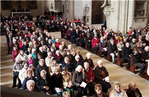 Das Foto zeigt sehr viele Menschen in einer großen Kirche sitzend.