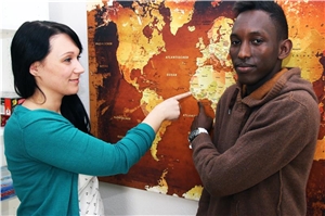 Auf dem Bild steht eine Frau und ein Mann vor einer Weltkarte und zeigen auf Westafrika