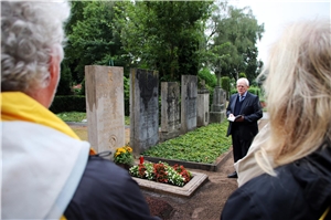 Auf dem Bild steht Domkapitular als 1. Vorsitzende des Diözesancaritasverbandes Josef Leenders vor einem Grab