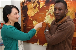Das Foto zeigt eine Frau und einen dunkelhäutigen jungen Mann vor einer Afrikakarte.