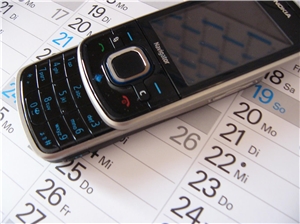 Das Foto zeigt ein Handy, das auf einem Kalenderausschnitt liegt.