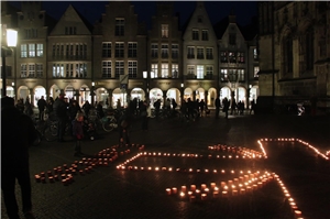 Das Foto zeigt einen Teil des Caritas-Logos als leuchtendes Kerzenbild im Dunkeln.