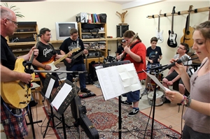 Das Foto zeigt Jugendliche bei einer Musikprobe mit Instrumenten und singend.