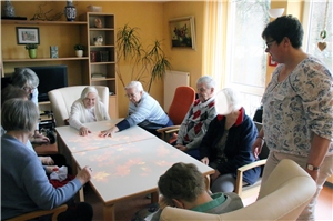Mehrere ältere Menschen sitzen spielend um einen Tisch