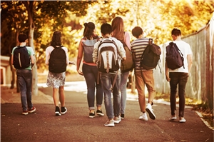 Das Foto zeigt eine Guppe von Schülern von hinten, die eine Straße entlanglaufen.