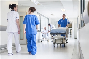 Das Foto zeigt einen Krankenhausflur, auf dem Pflegemitarbeiter laufen.