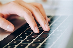 Das Foto zeigt eine Hand auf einer Laptop-Tastatur.