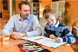 Das Foto zeigt einen Vater mit seinem Sohn bei Hausaufgaben.