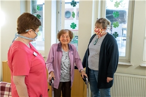 Das Foto zeigt eine ältere Dame und rechts sowie links eine Betreuerin im Altenheim.