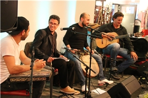 Vier Musiker spielen auf einer kleinen Bühne auf ihren Instrumenten