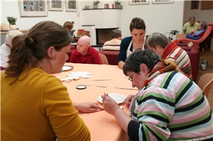 Das Foto zeigt ältere Menschen mit Behinderung und Betreuerinnen an einem Tisch.