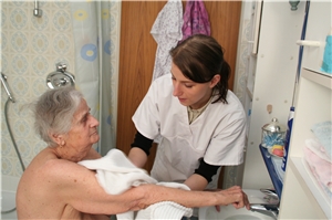 Das Foto zeigt die Mitarbeiterin einer Sozialstation, die den Arm einer alten Frau wäscht.