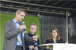 Dr. Frank John. Hensel steht bei der Kundgebung der LAG Freie Wohlfahrtspflege NRW zur Kampagne 'NRW belib sozial!' neben einer Moderatorin und Verena Schäffer MdL auf einer Bühne und redet 