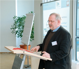 Heinz Janning steht beim 2. Einführungsworkshop für das Projekt "win-win für Alle!" an einem Rednerpult und hält eine Präsentation