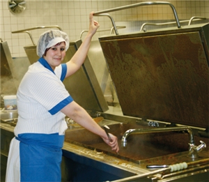 Melissa Zacher steht vor einem großen Behälter mit kochendem Essen in der Großküche des Studentenwerks Essen-Duisburg