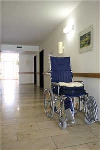 Leerer Rollstuhl in einem kahlen Gang einer Pflegestation