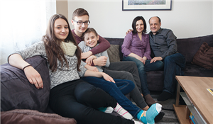 Die fünf Mitglieder der Familie Demiri sitzen auf ihrem Sofa und blicken in die Kamera. Die Kinder sitzen auf der linken und die Eltern auf der rechten Seite des Sofas.