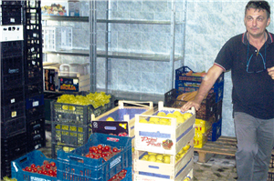 Ein Mitarbeiter der Associazione Terza Settimana steht in einem Lagerraum neben einigen Obst- und Gemüsekisten