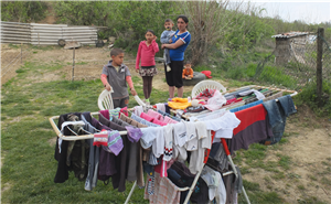 Eine Romafamilie (Mutter mit je zwei Mädchen und Jungen) steht in einem heruntergekommenen Garten vor einem gefüllten Wäscheständer