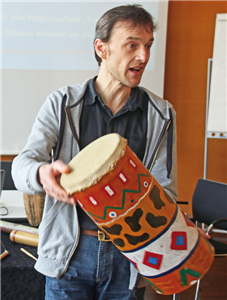 Christoph Studer, der eine bunt bemalte, afrikanische Trommel in den Händen hält