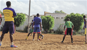 Eine Gruppe junger Afrikaner, die auf einem Sandplatz Fußball spielen