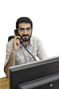 Porträt: Mohamad Jazmati, der vor einem Computer sitzt und einen Telefonhörer in der Hand hält