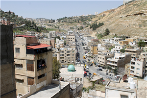 Ein Ausschnitt der jordanischen Hauptstadt Amman mit Häuser, Bergen und einer langen Straße
