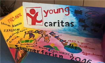 Eine bunt bemalte Bank aus Holz mit Bilder und Sprüchen, sowie einem gemalten Logo der youngcaritas