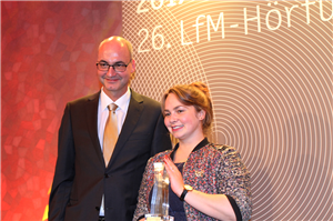 Markus Lahrmann und Sabrina Droste stehen beim 26. LfM-Hörfunkpreis am 24. November 2017 zusammen auf der Bühne. Sabrina Droste hält den 'Sozialpreis NRW' in den Händen.