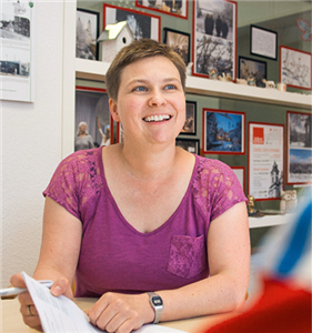 Beraterin Gaby Keil in den Räumlichkeiten des 'zentrum plus' in Düsseldorf-Oberbilk. Im Hintergrund ist ein Regal mit Bildern und Dekoration zu sehen.