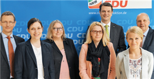 Ein Gruppenfoto Gruppenfoto mit dem AK Integration der CDU-Fraktion NRW und Caritas-Vertreter/innen vor einem Faltdisplay der CDU NRW