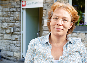 Porträt: Simone Holzapfel vor der Eingangstür des Café Plattform in Aachen