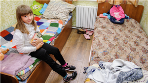 Ein ukrainisches Mädchen sitzt in einem Zweibettzimmer der Wohlfahrtsorganisation 'The Way Home' in Odessa (Ukraine) auf einem Bett und hält Süßigkeiten in der Hand